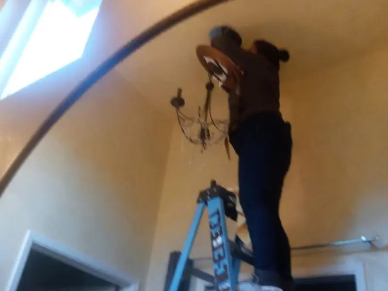 Electrician installing a chandelier in a Rancho Mission Viejo residence